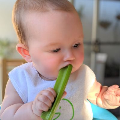 Baby with stick of celery in mouth