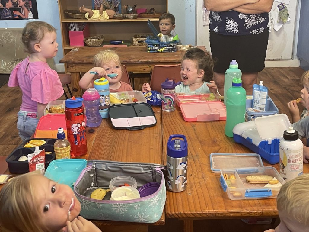Children enjoying a lunch team meal together in daycare environment