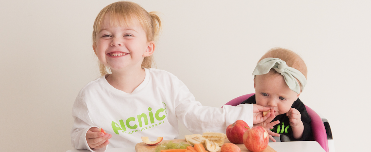 little baby sister stealing food out of older sisters hand with her mouth