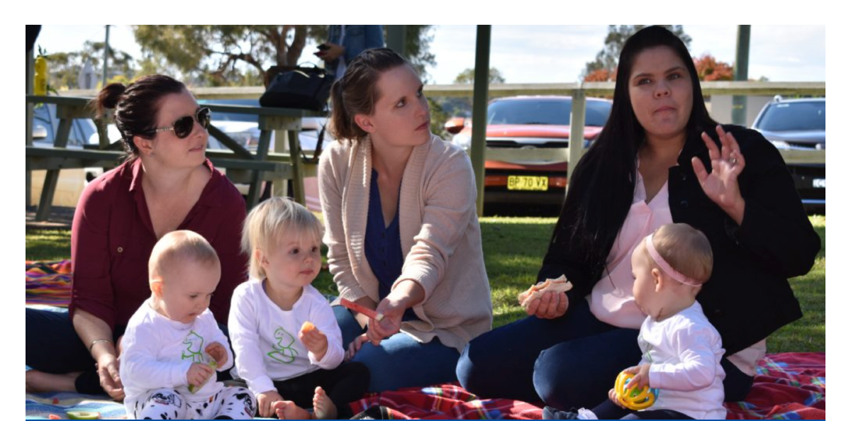 Parents eating mid meal on rug with children