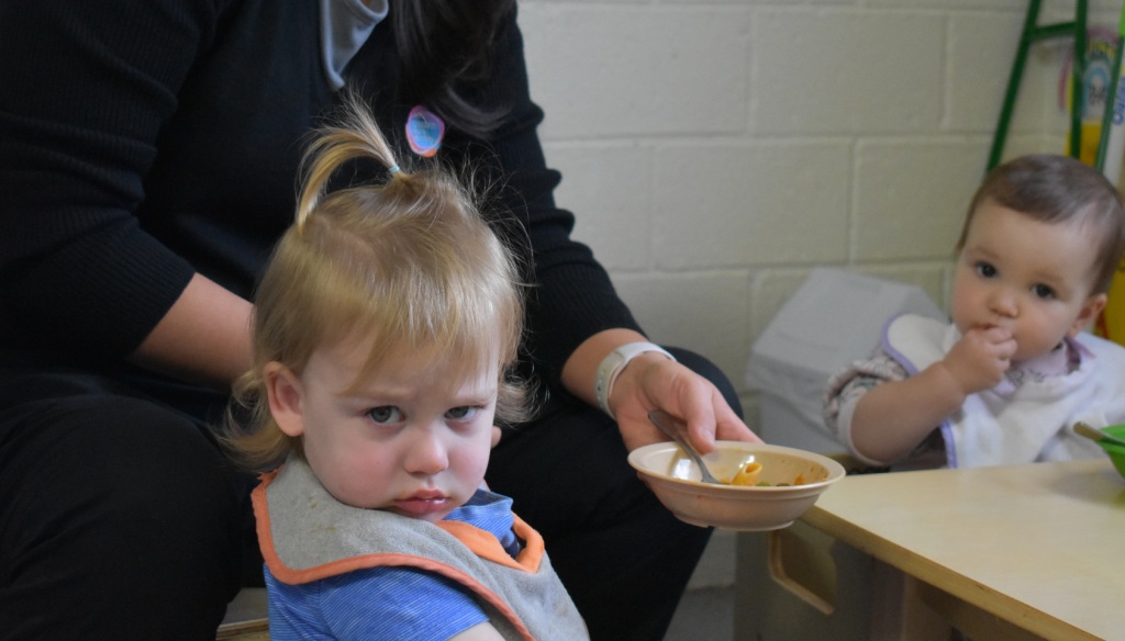 Toddler frowning at the camera at mealtime.