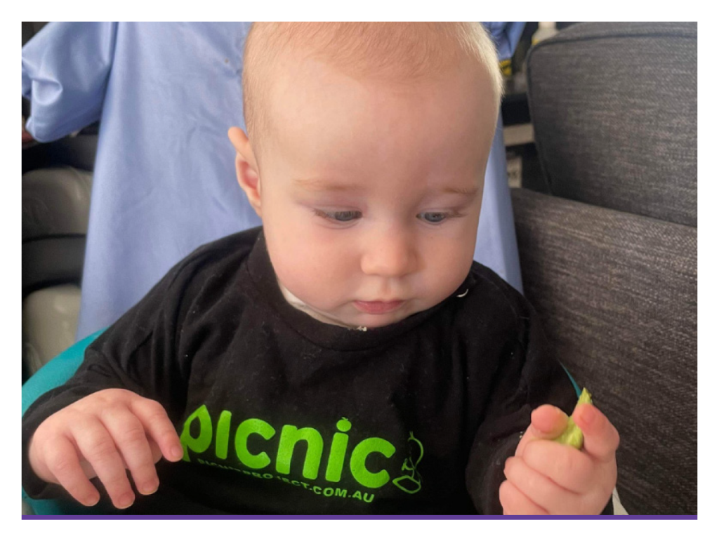 baby holding cucumber slice