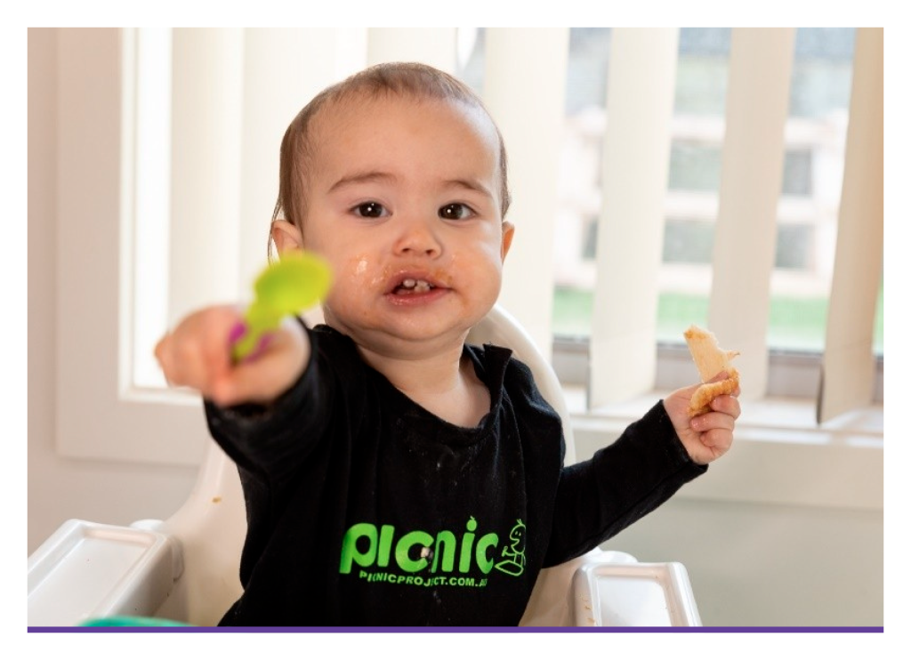 baby holding a spoon out towards the camera
